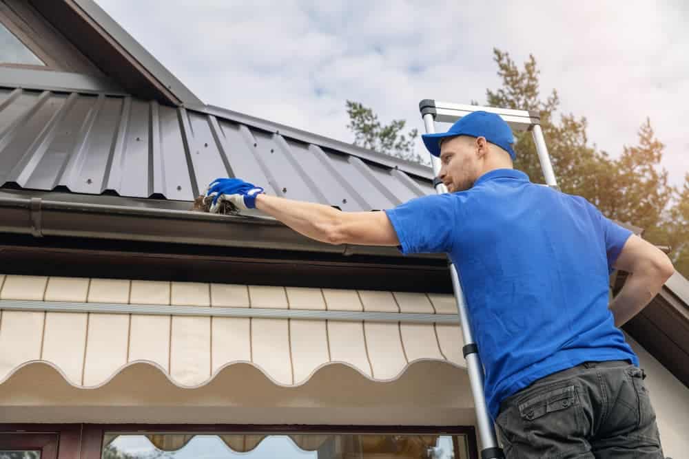 Man cleaning dirty gutter — Gutter Systems in Sydney, NSW